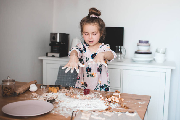 Cute baby girl 4-5 year old playing with flour and dough in kitchen closeup. Cooking child indoors.  - Photo, Image