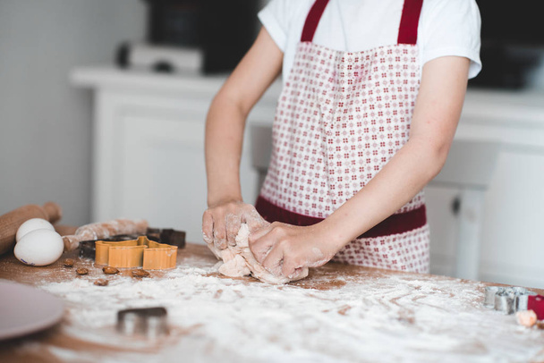 Mädchen knetet rohen Teig in Nahaufnahme. Kochen in der Küche Kindheit.  - Foto, Bild