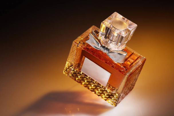 Bottle of perfume on a yellow background with reflection. - 写真・画像