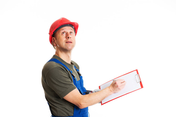 young workman in blue dungarees with clipboard in front of white background - Photo, image