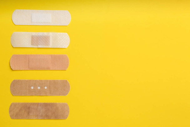 Different types of sticking plasters on yellow background, flat lay. Space for text - Fotoğraf, Görsel