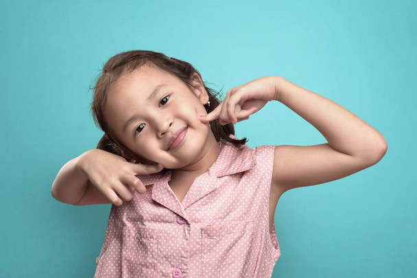 Happy asian little girl with funny expression against blue background - Foto, Imagem
