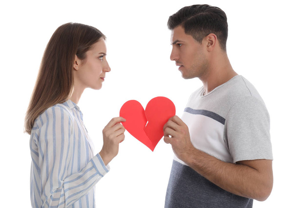 Couple tearing paper heart on white background. Relationship problems - Photo, image