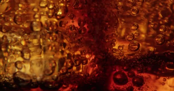 Macro di bolle di Cola e cubetti di ghiaccio in un bicchiere girato su rosso
 - Filmati, video