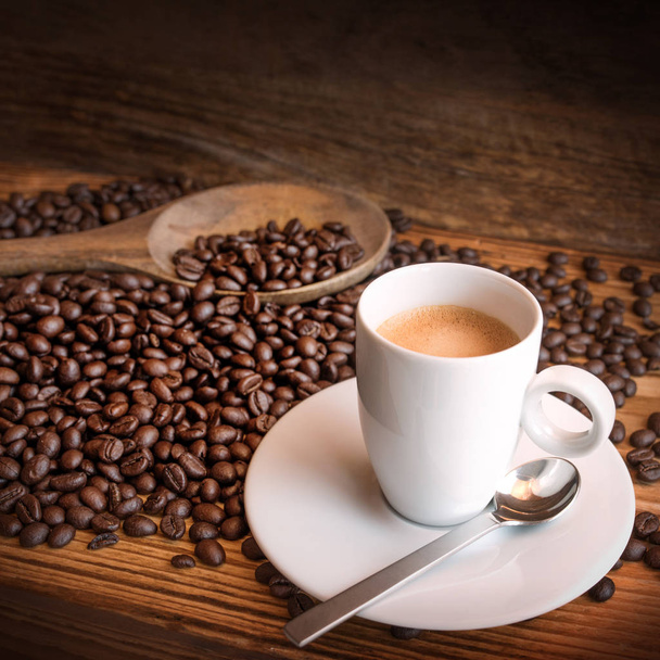 close up of cup of espresso with fresh beans on a wooden table - Photo, image
