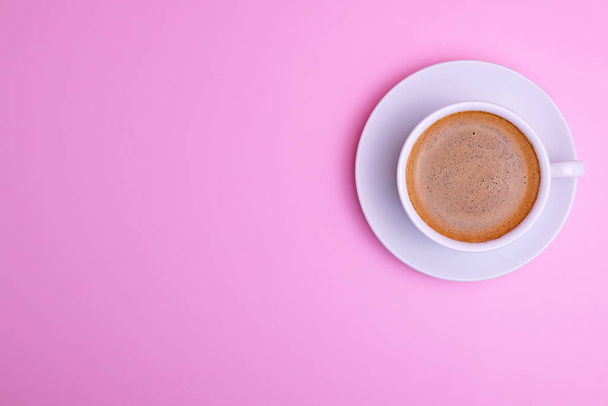 White cup and saucer on a pink background, drink black coffee, top view - Фото, зображення