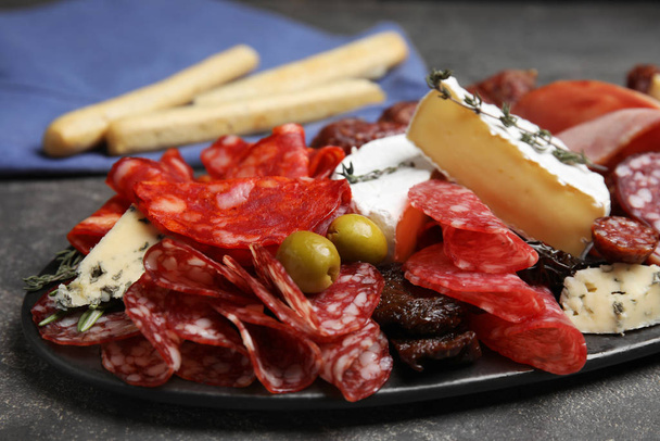 Tasty salami and other delicacies served on grey table, closeup - Фото, зображення