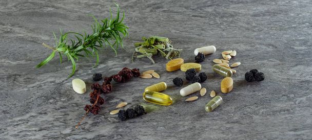 φάρμακα χάπια τροφίμων suplements υγιεινή ιατρική φαρμακευτική αγωγή θεραπεία πρόσθετα φαρμακευτική φαρμακευτική βιομηχανία σε γκρι φόντο με πράσινα φυτά - Φωτογραφία, εικόνα