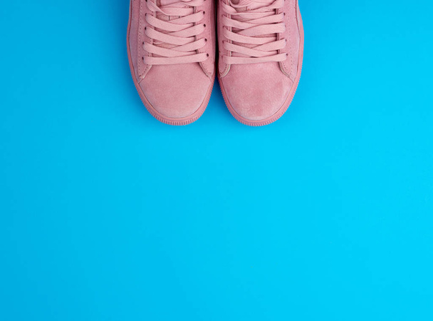 par de zapatillas deportivas de color rosa con cordones sobre un fondo azul
 - Foto, imagen