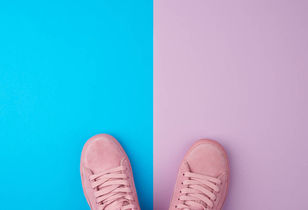 pair of sports pink sneakers with laces on a blue background, to - Foto, imagen