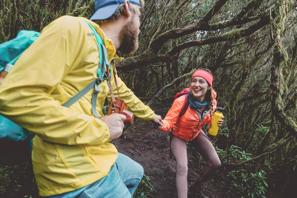 Young couple doing forest excursion - Happy people having fun discovering nature woods - Youth travel lifestyle concept - Photo, Image