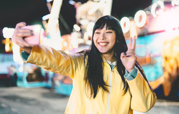 Asiatin macht Selfie mit Handy im Freizeitpark - Glückliche Frau hat Spaß mit neuen Trends Smartphone-Apps - Generation der Millennials und Social-Media-Sucht - Foto, Bild