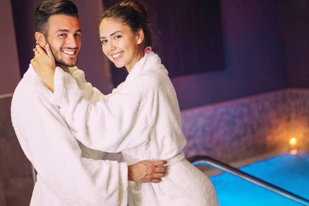 Szczęśliwa para bawiąca się w basenie luksusowy hotel uzdrowiskowy - Romantyczny młodzież robi relaksujący zabieg wellness razem - Love relationship and health lifestyle concept - Zdjęcie, obraz