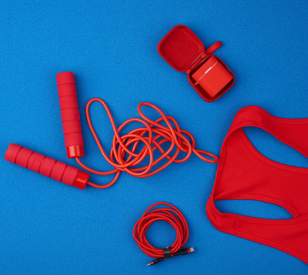 Rotes Sporthemd, rotes Springseil und drahtlose Kopfhörer in Rot - Foto, Bild