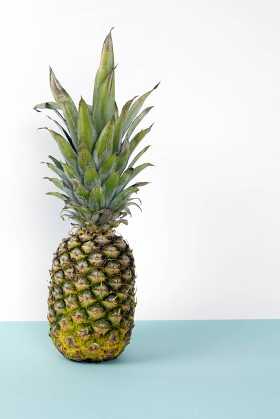 Playful pineapple on a pop bicolor background turquoise and white like horizon. Minimal design still life photography. - Фото, изображение