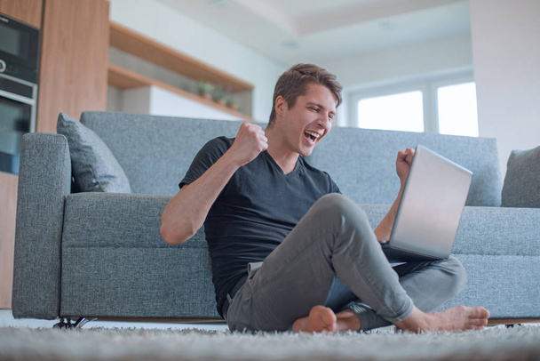 cheerful man watching a video sitting on the floor in the living room - Photo, Image