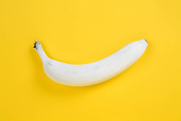.a white banana on a yellow background. Colors have been reversed..Fun, minimal and quirky color still life photography - Foto, imagen