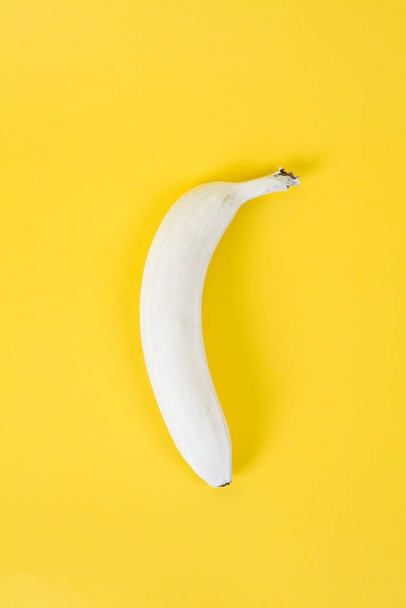 .a white banana on a yellow background. Colors have been reversed..Fun, minimal and quirky color still life photography - Zdjęcie, obraz