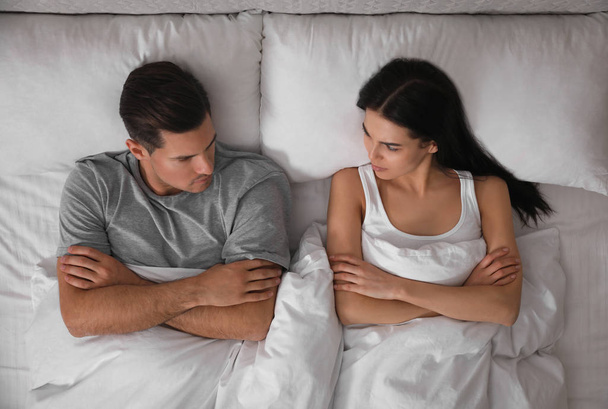 Couple with relationship problems in bed at home, top view - 写真・画像