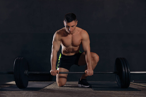 Strong man lifting barbell in modern gym - Фото, изображение