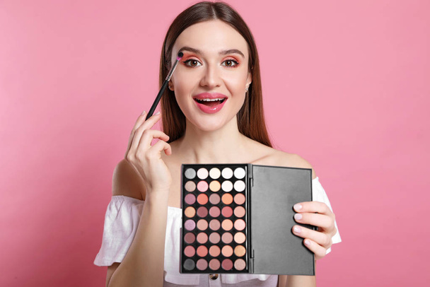 Beauty blogger applying eyeshadow on pink background - Foto, immagini