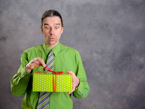 young  man in green shirt and necktie with green gift box is surprised - Фото, зображення