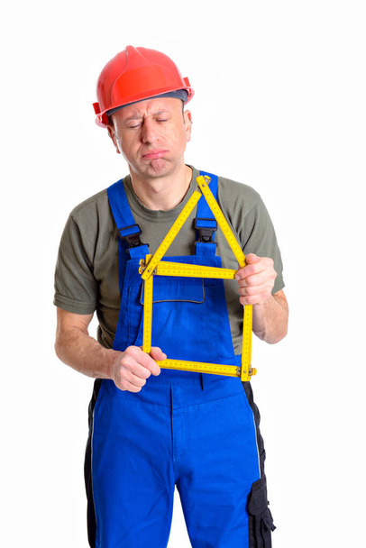 dissatisfied worker with yardstick- house in front of white background - Photo, image