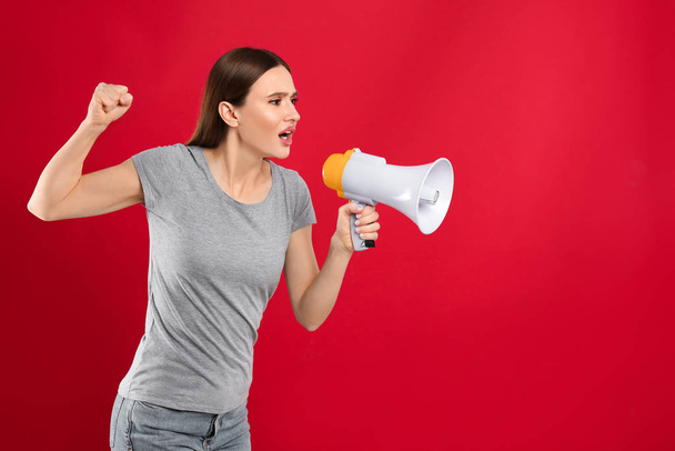 Young woman with megaphone on red background - Photo, image