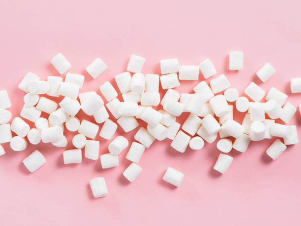 Marshmallows on pink background with copyspace. Flat lay or top view. Background or texture of colorful mini marshmallows. Winter food background concept. - Фото, изображение
