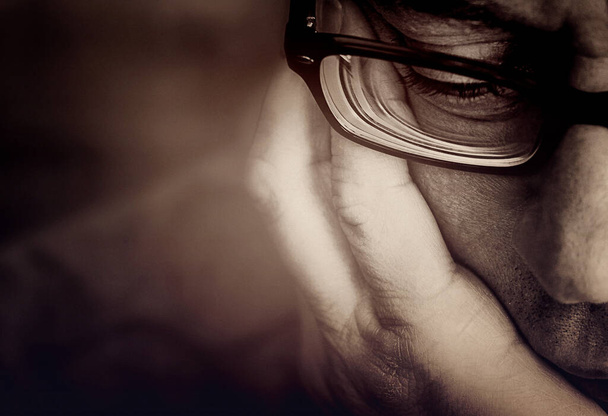 partial view of a male face with glasses and supporting hand,retro,dark sepia tint - Zdjęcie, obraz