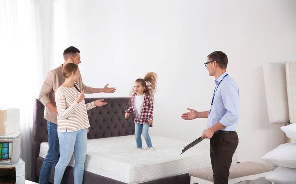 Salesman showing family mattress in furniture store - Foto, Imagem