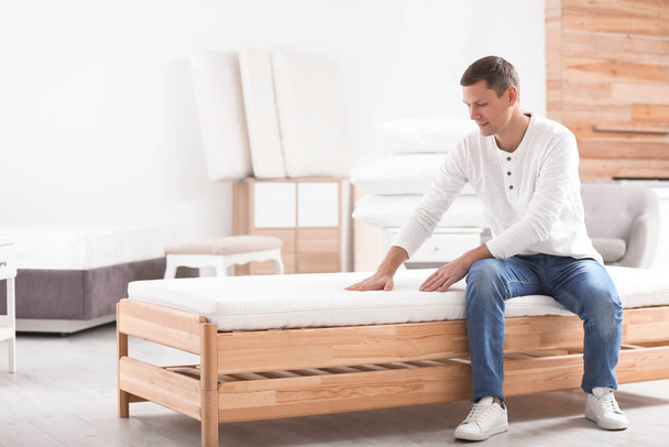 Man touching mattress in furniture store. Space for text - Foto, imagen