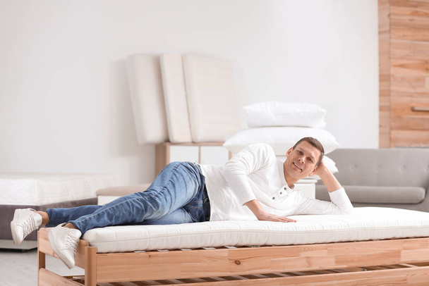 Man testing soft mattress in furniture store - 写真・画像