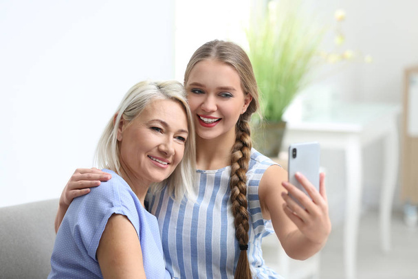 Happy mother and daughter taking selfie at home - Fotó, kép