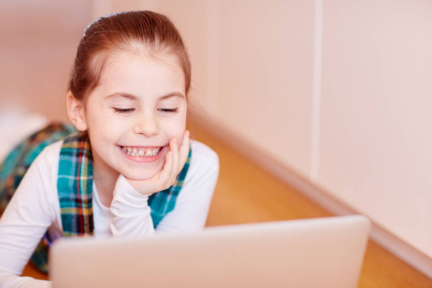 Симпатичная маленькая девочка, играющая на ноутбуке - Фото, изображение