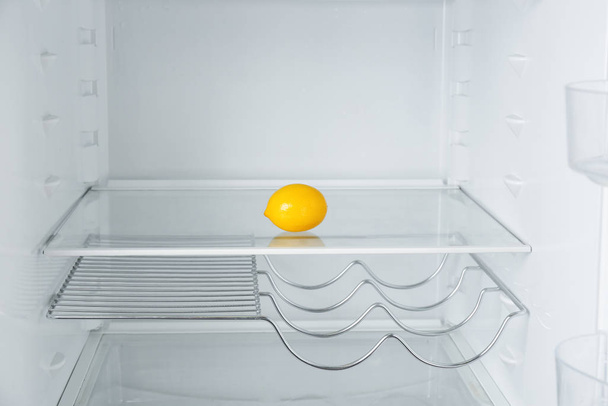 Fresh organic lemon on empty shelf in refrigerator - Фото, зображення