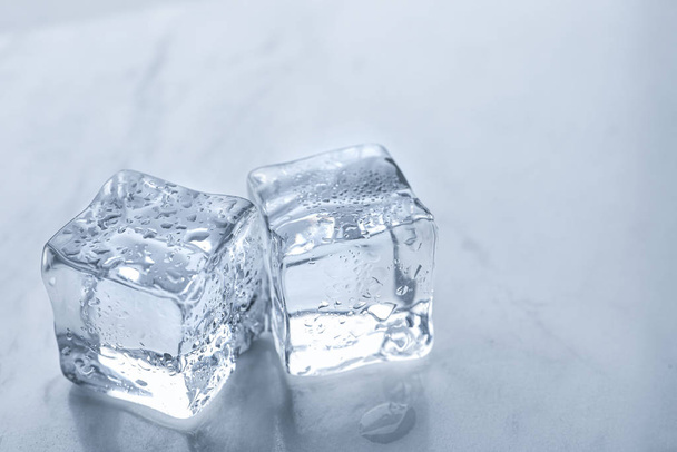 Crystal clear ice cubes with water drops on light table, closeup - Foto, Bild
