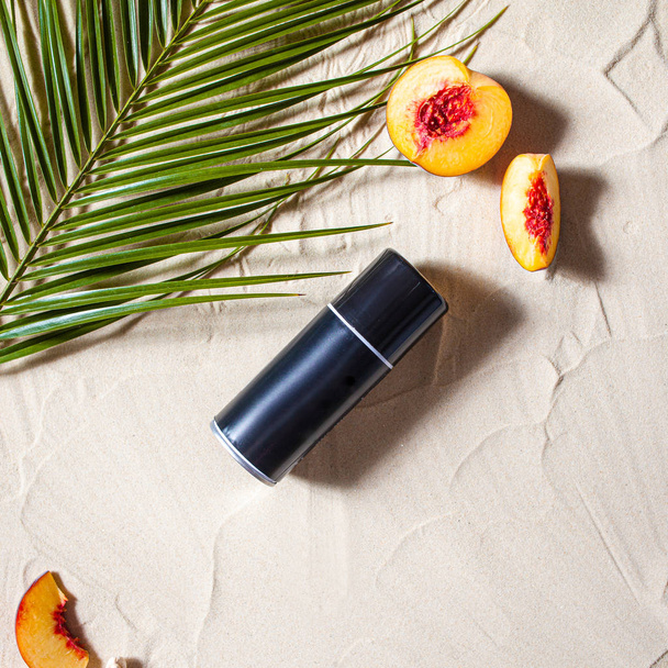 Wonderful beach. Stylish black spray lies on the beach sand, surrounded by juicy fruits, starfish, and palm leaves. - Foto, Bild