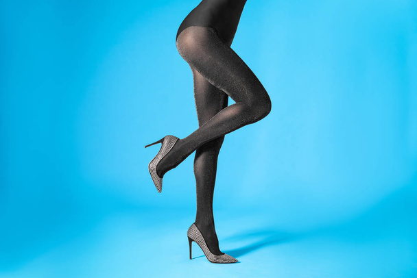 Woman wearing black tights and stylish shoes on blue background, closeup of legs - 写真・画像