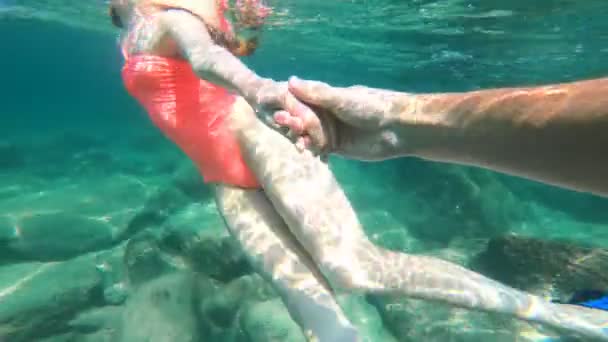 Follow me. Young woman leading boyfriend into turquoise see waters, underwater film. - Footage, Video
