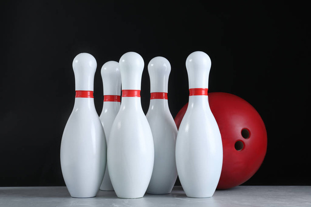 Red bowling ball and pins on grey stone table - Φωτογραφία, εικόνα