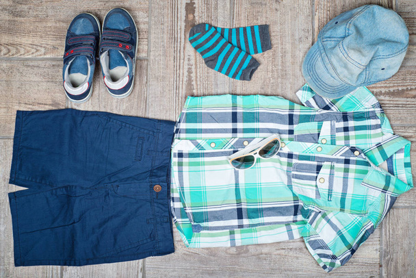 Flat lay picture of boy's casual outfit. Boy's casual outfit on wood board background - Foto, Imagem