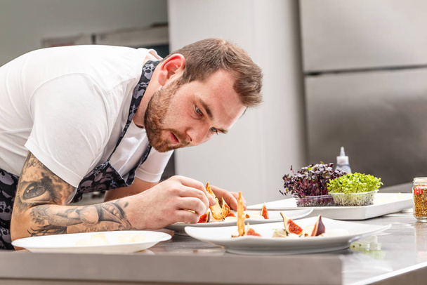 The chef is garnishing appetizer dish in a restaurant kitchen - Foto, Imagen