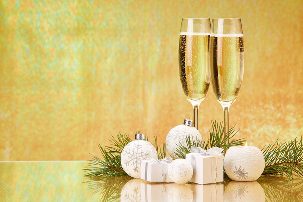 Two glasses with champange, fir tree branch, gift boxes and christmas decorations on a golden background.  New year and Christmas. - Photo, Image