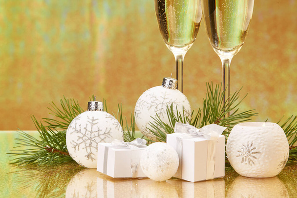 Two glasses with champange, fir tree branch, gift boxes and christmas decorations on a golden background.  New year and Christmas. - Фото, изображение