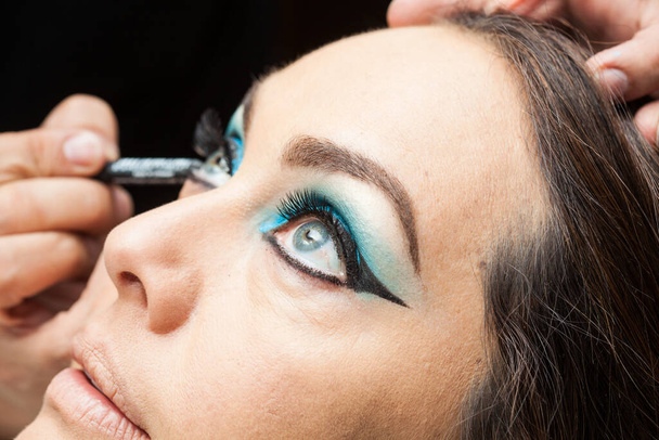 Makeup artist applying blue eyeshadow on white woman eyes - Foto, Bild