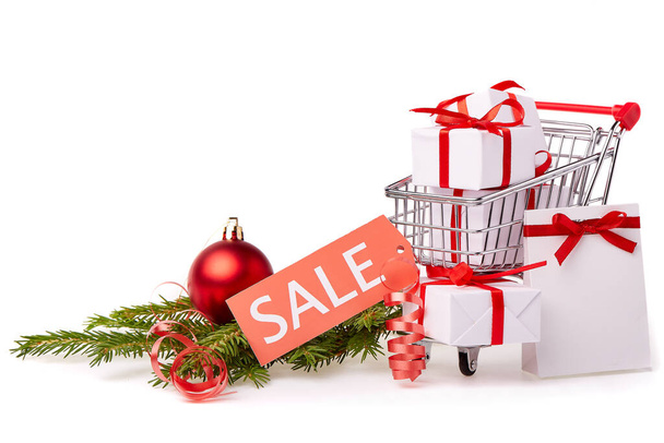 Shopping trolley with gift boxes and brenches of fir-tree with decoration on a white background. Christmas and New Year sale. - Fotoğraf, Görsel