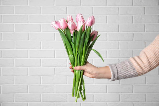 Woman with beautiful pink spring tulips near white brick wall, c - Foto, imagen
