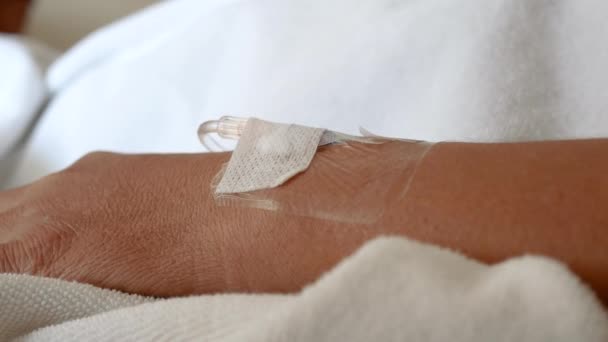Detailní záběr ruky pacienta přijímajícího intravenózní tekutinu přímo do žíly na rozmazaném luxusním pozadí Vip místnosti v nemocnici. Asijská žena s hospitalizací. - Záběry, video