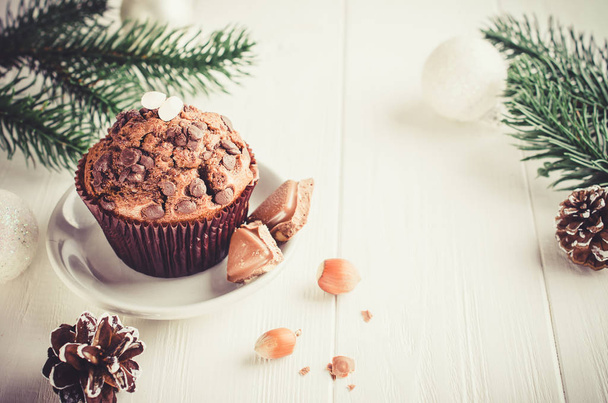 Chocolate muffin and branches fir on white wooden background. Selective Focus. Copy space. Vintage stile. Toned image - Φωτογραφία, εικόνα